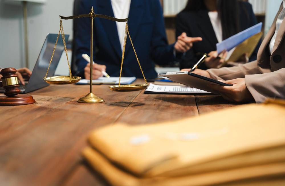 Three paralegals at the end of large wooden desk with a judge discussing legal documents.