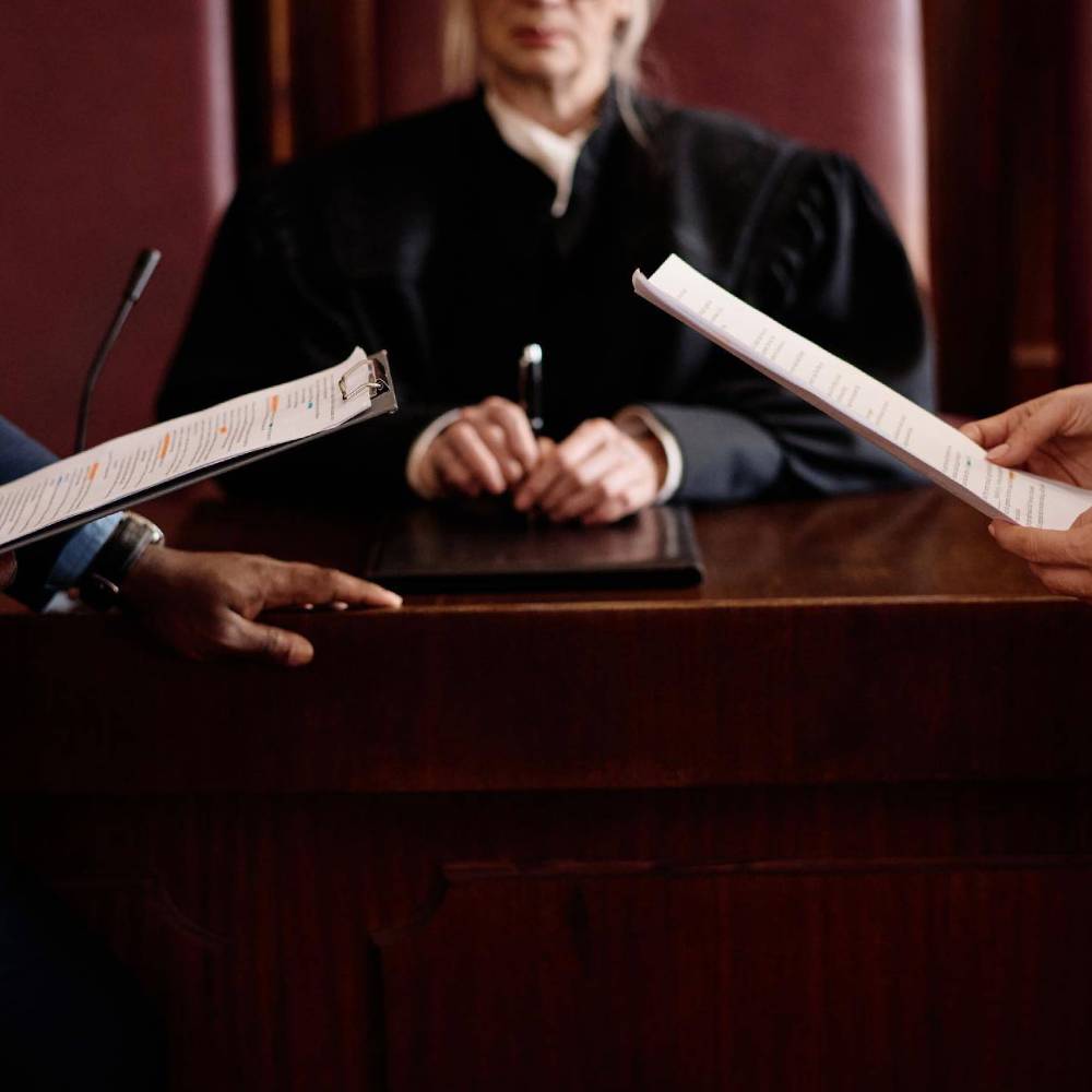 Close up of two lawyers hands on legal documents in court in front of a judge.